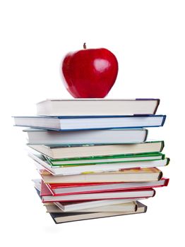 A stack of text books with a big, red apple on top.  Shot on white background.