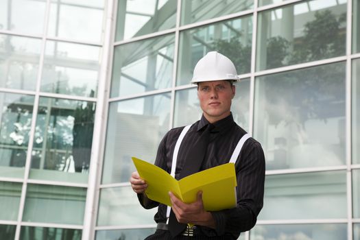 A foreman holding a folder outside of the office.