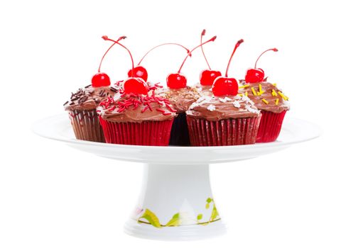 Decadent chocolate cherry cupcakes arranged on a pedestal cake plate.  Shot on white background.