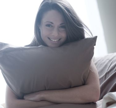 Young woman embracing her pillow in the morning