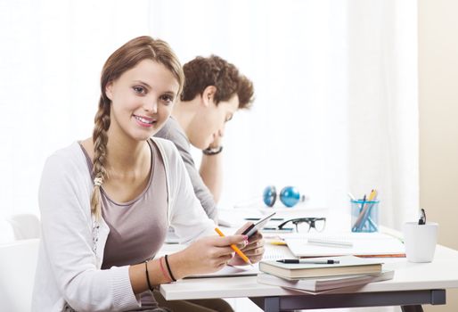 Teen boy and girl sitting together and studying 