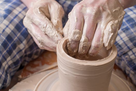 Hands of a potter, creating an earthen jar on the circle