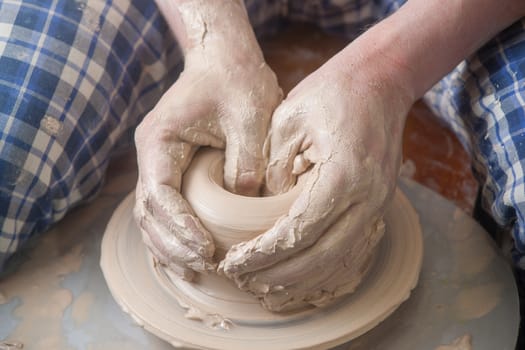 Hands of a potter, creating an earthen jar on the circle