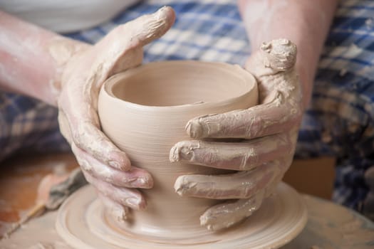 Hands of a potter, creating an earthen jar on the circle