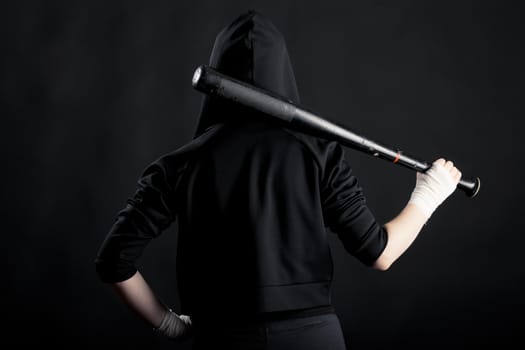 Young woman with a baseball bat. View from the back. street hoodlum