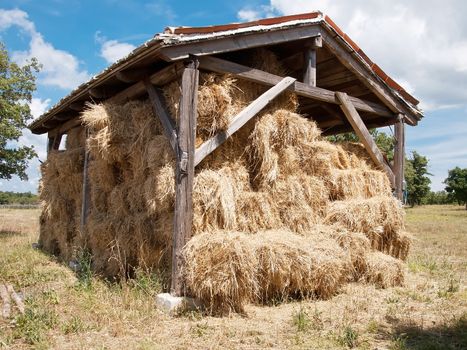 open wooden barn full of hay bale