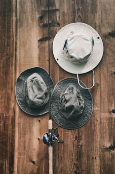 Fishing hats and pole against wood wall