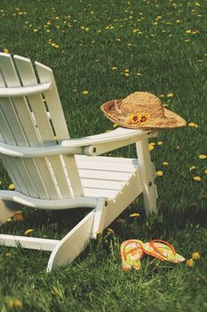 Straw hat on adirondack chair in the grass