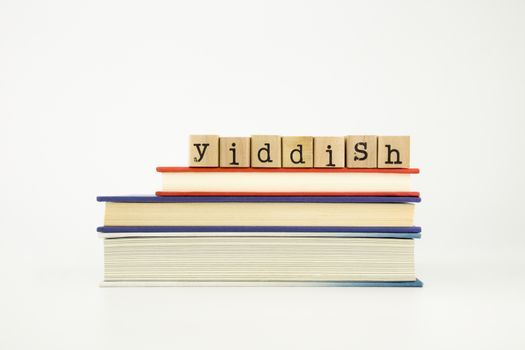 yiddish word on wood stamps stack on books, foreign language and translation concept