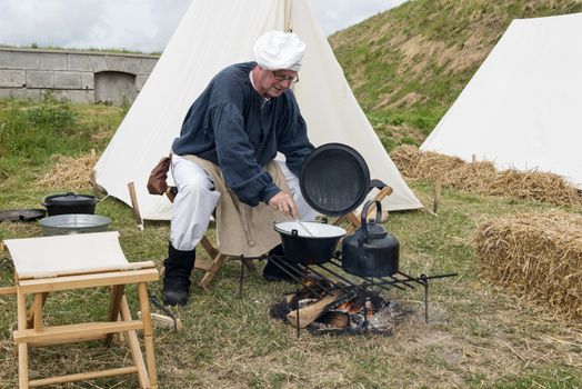 HELLEVOETSLUIS,NETHERLANDS - JUN 28: Man in traditional costume cooking on campfire during the event of the conquest of Hellevoetsluis in 1813