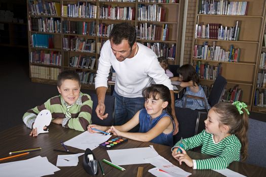 A teacher with his elementary students in the school library.
