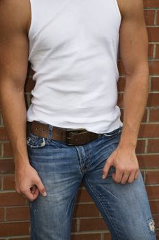 A muscled male body in jeans & white tank top.