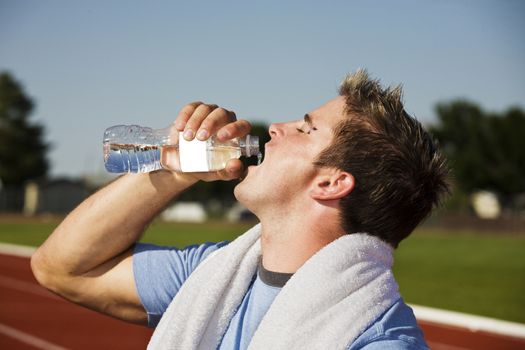A thirsty athlete splashes some water down his throat after running a race.