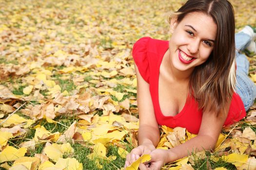 Fall portrait of a smiling girl laying in the leaves.