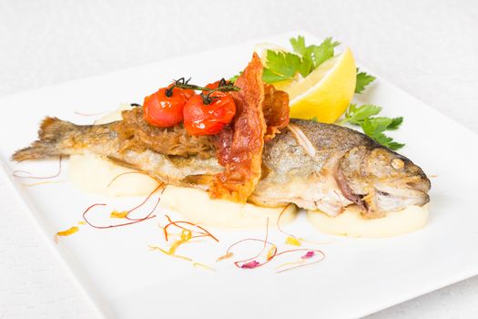 Fried fish on a white decorated plate.