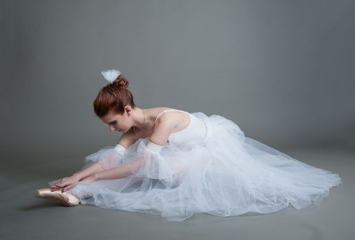 dancer in the white tutu dancing on a grey background