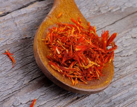 Saffron in Wooden Spoon closeup on Rustic Wooden background