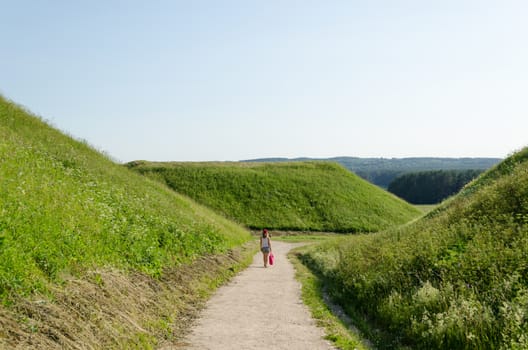 tourist girl walk between mound hills in Lithuanian historic capital Kernave, UNESCO World Heritage Site.