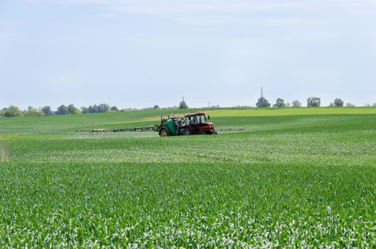 tractor with nozzles fertilizing grown crops from diseases and pests