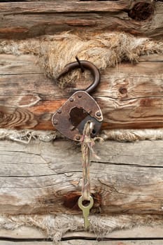 old padlock with key on a background of a timber wall