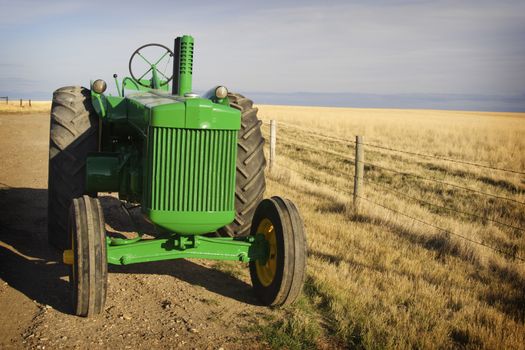 Sunlit vintage diesel tractor restored & freshly painted, on prairie Canadian farm.