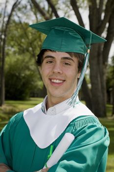 A happy young graduate, smiling & proudly holding his degree.