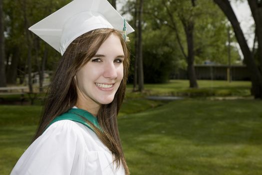 A happy, smiling girl in graduation cap & gown.