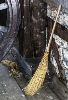 Old fashioned hand crafted straw broom propped up against wall. 