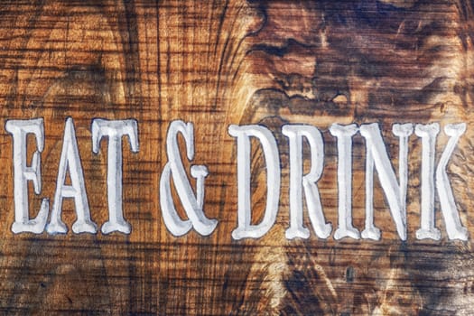 Old time wooden tavern sign with eat and drink printed. 
