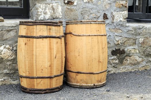 Two wooden hand crafted barrels against cobblestone house. New wood contrasts with old stone. 