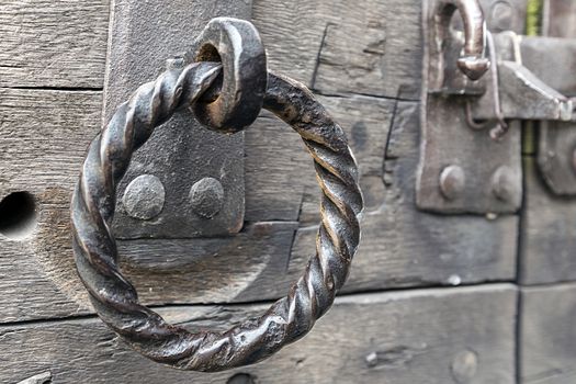 Grungy antique iron door ring on old weathered wooden door. 