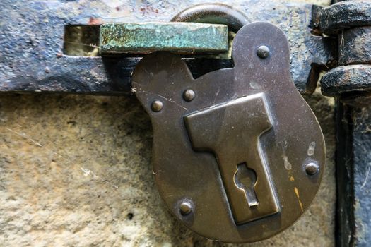 Old fashioned heavy metal padlock with keyhole. Hook and latch on door.