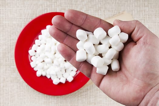 Miniature Marshmallows in a male hand. A food ingredient.