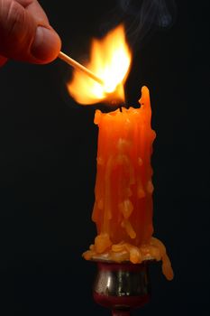 Hand lighting a candle with match stick 