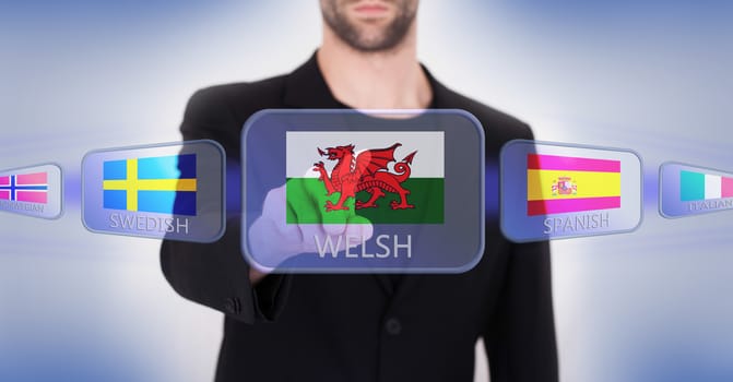 Hand pushing on a touch screen interface, choosing language or country, Wales