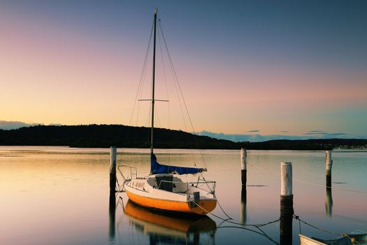 Little sailing boat or yacht tied to its moorings.  Sunrise at Woy Woy, N/SW, Australia.  Woy Woy is aboriginal Wy Wy, which  means "much water" or "big lagoon"