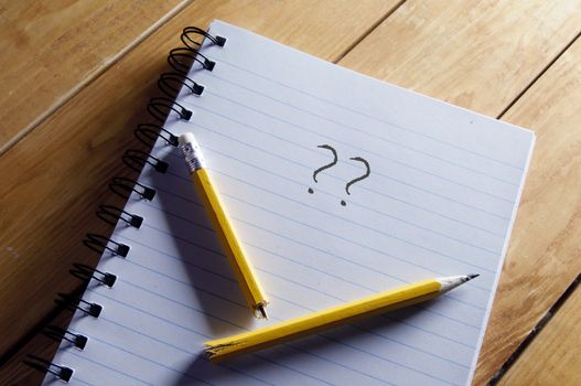 Questions mark and broken pencil on top of a note pad