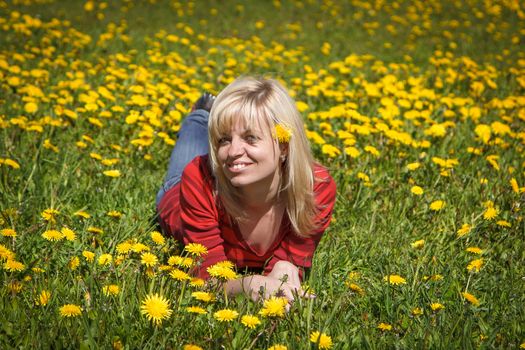 A smiling woman laying down in a dandelion field