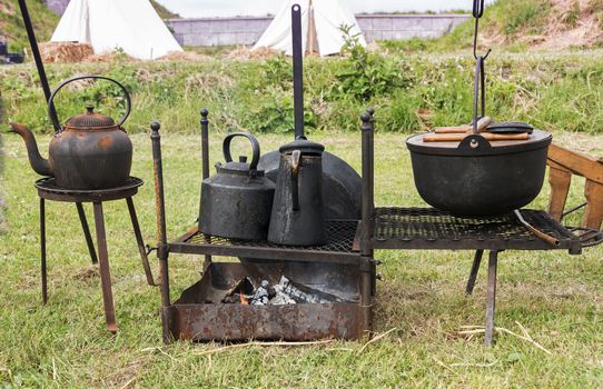 camping cooking on campfire with old iron pots 