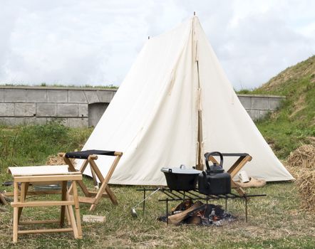camping with tent and cooking equipment on campfire