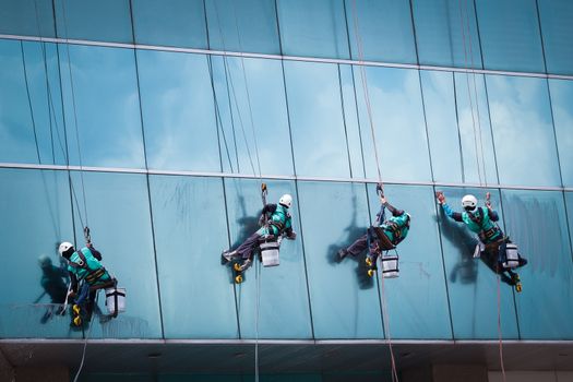 group of workers cleaning windows service on high rise building