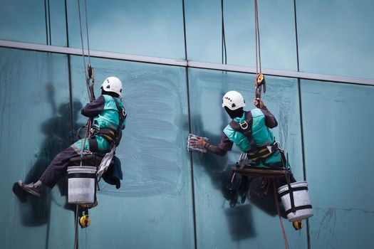 group of workers cleaning windows service on high rise building