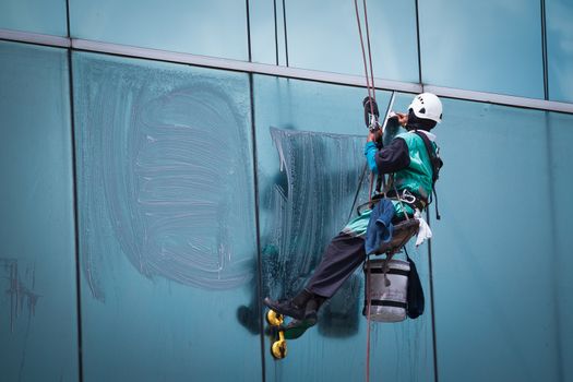worker cleaning windows service on high rise building