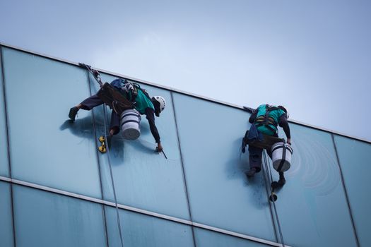 group of workers cleaning windows service on high rise building