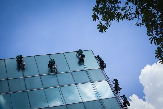group of workers cleaning windows service on high rise building
