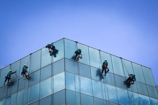 group of workers cleaning windows service on high rise building