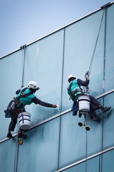 group of workers cleaning windows service on high rise building