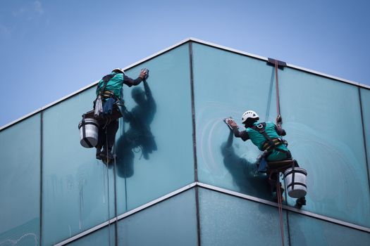 group of workers cleaning windows service on high rise building