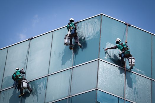 group of workers cleaning windows service on high rise building