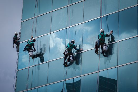 group of workers cleaning windows service on high rise building